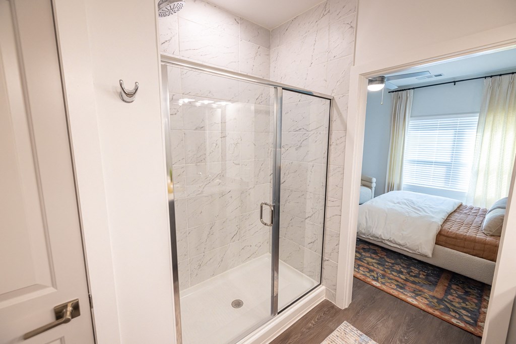 a glass shower in a bedroom with a bed