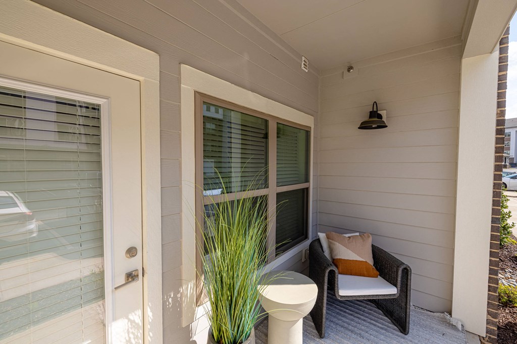a small porch with a chair and a toilet and a window