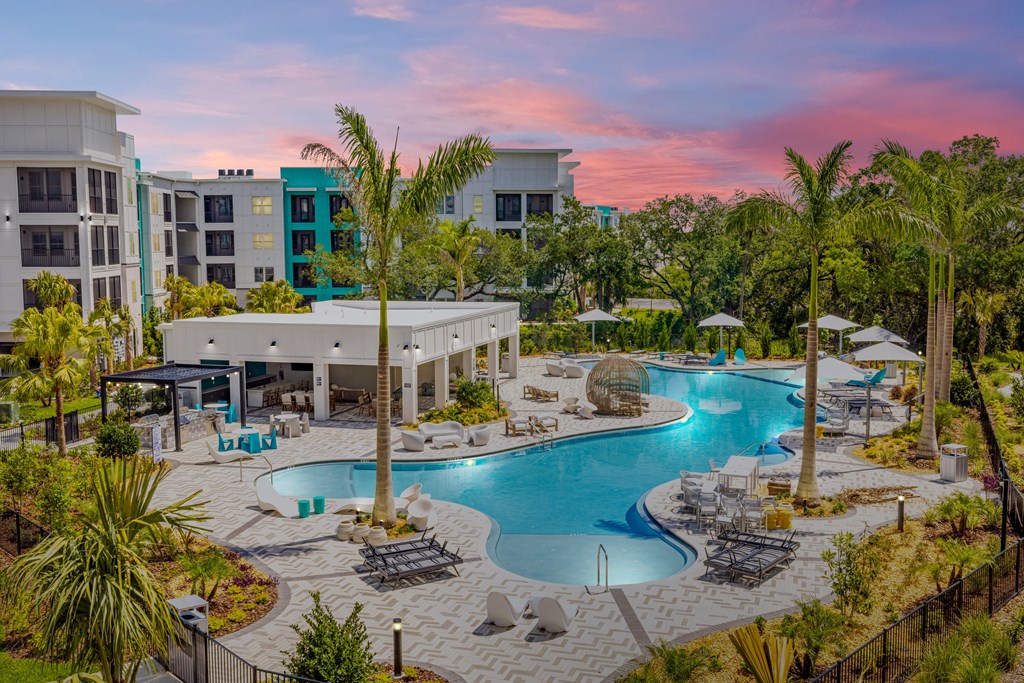 a resort pool with palm trees and buildings at sunset
