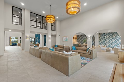 A spacious living room with a long couch and a chandelier hanging from the ceiling.