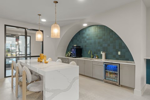 A modern kitchen with a white marble island and a curved blue backsplash.