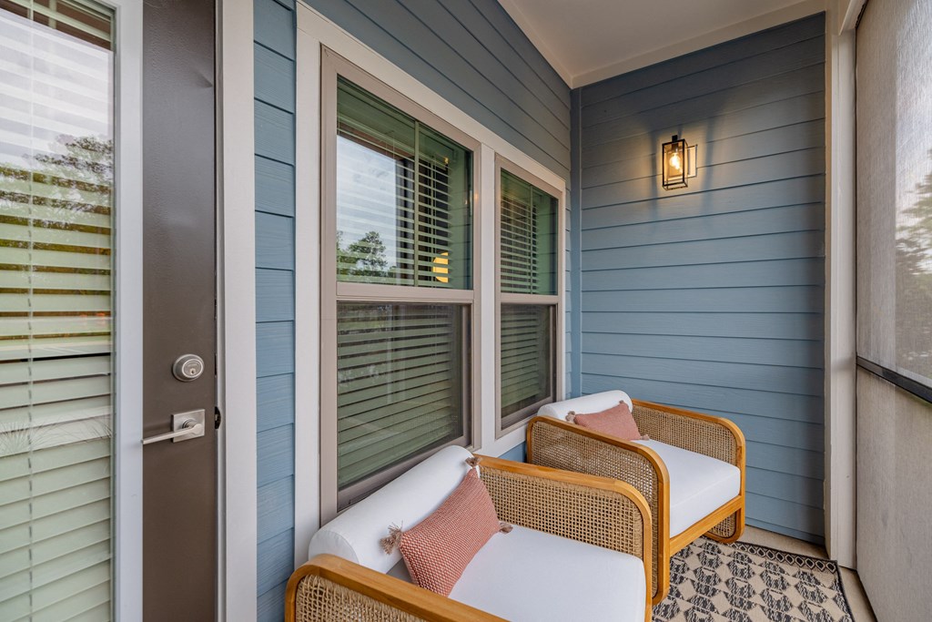 a porch with two wicker chairs and a door