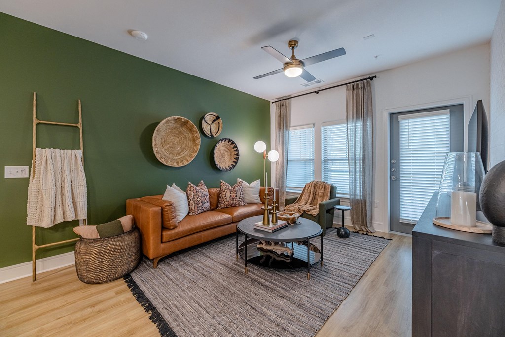 a living room with green walls and a ceiling fan