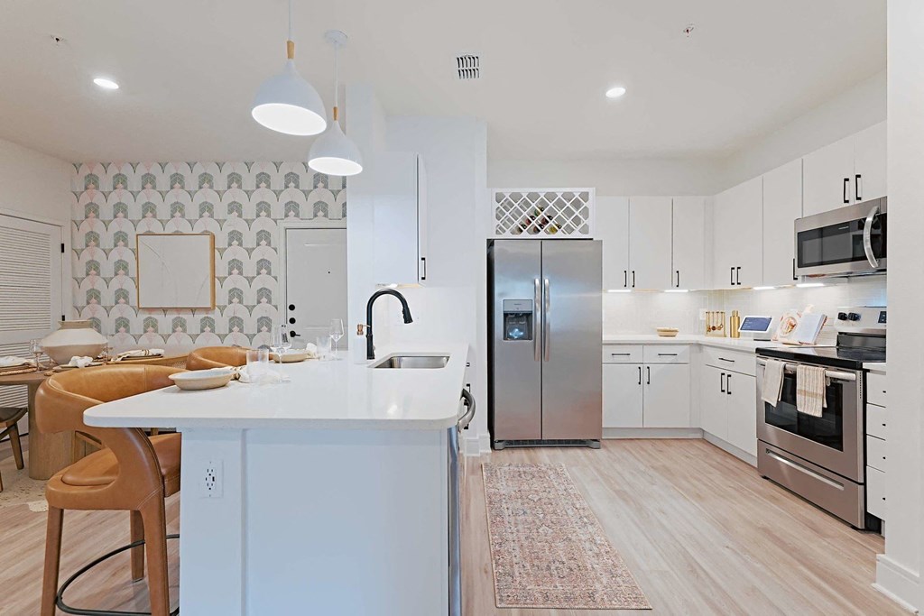 a kitchen with a white counter top and a stainless steel refrigerator