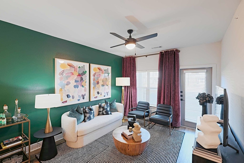 a living room with green walls and a ceiling fan