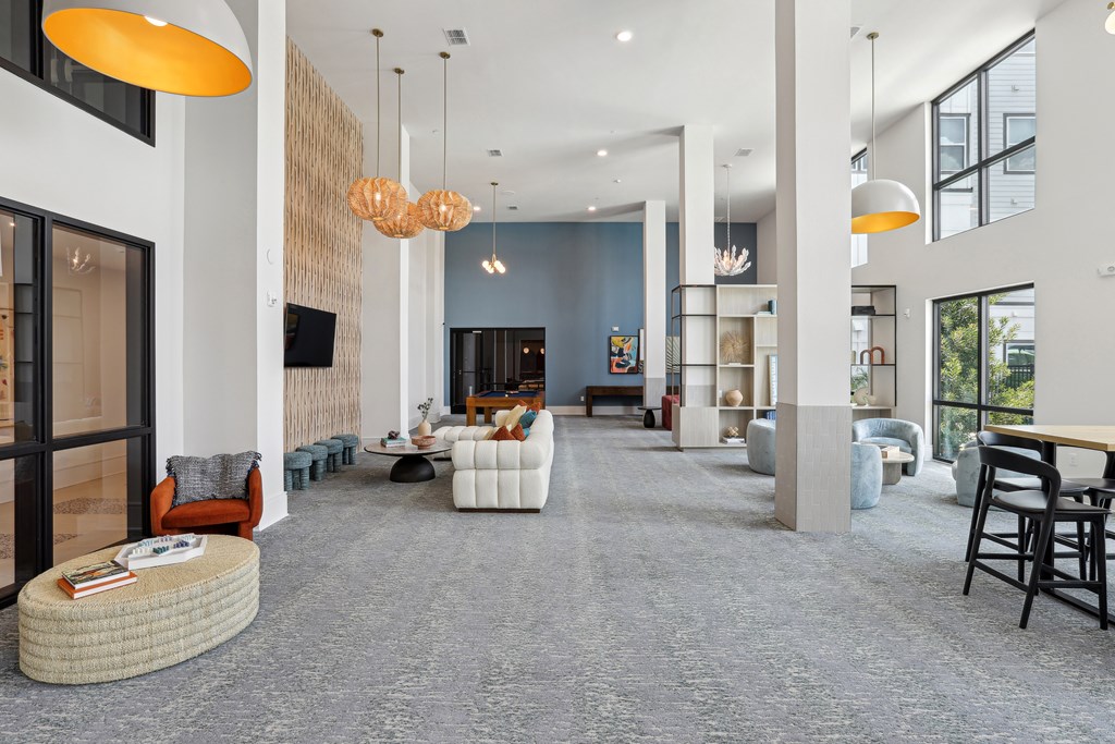 A spacious living room with a grey carpet and modern furniture.