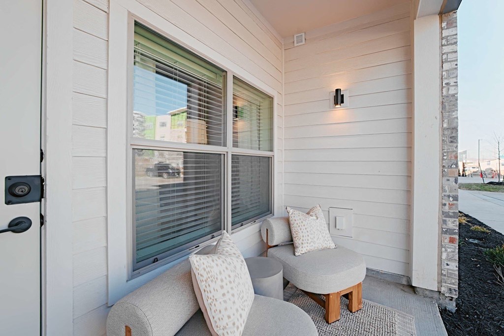a small porch with two couches and pillows and a window
