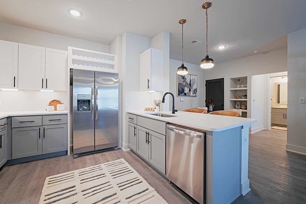 a large white kitchen with a blue island and stainless steel refrigerator