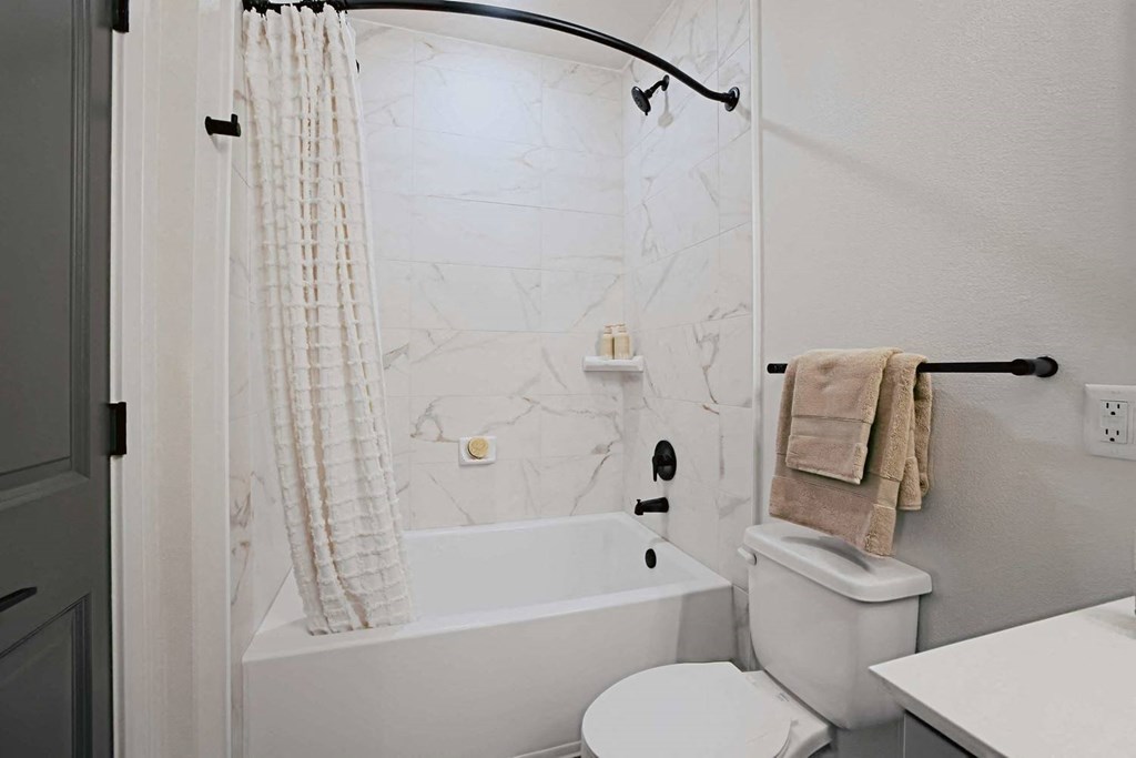 a white bathroom with a toilet and a tub