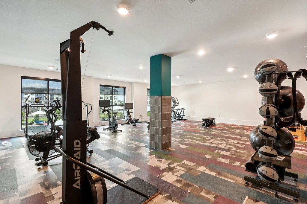 a gym with weights and other exercise equipment in a room with windows
