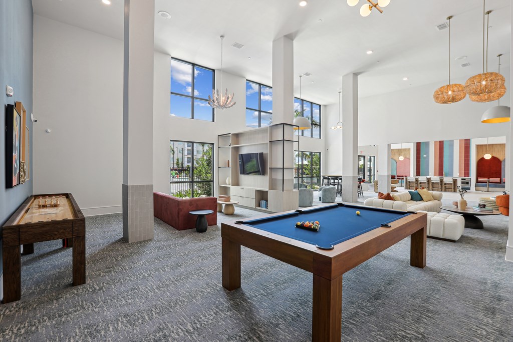 A billiard table is in the middle of a room with a pool table and a foosball table.