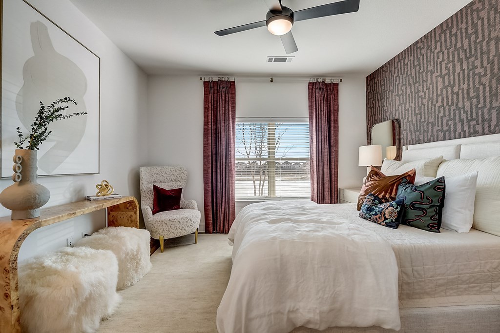 a bedroom with a large bed and a chair and a ceiling fan
