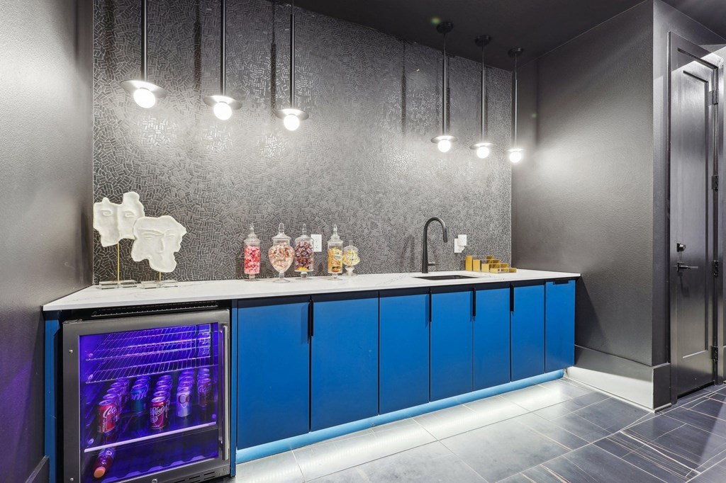 a home bar with blue cabinets and a stainless steel refrigerator