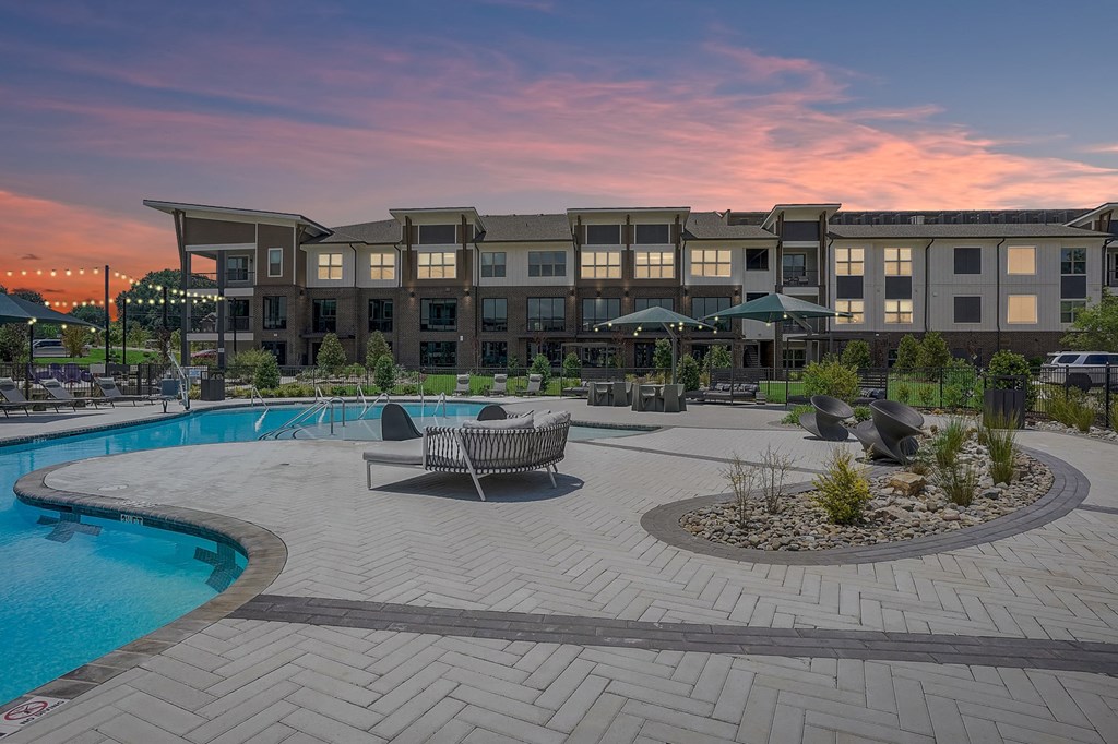 an outdoor area with a swimming pool and an apartment building in the background
