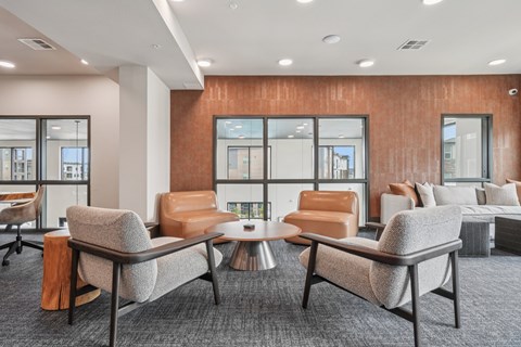 A modern office lounge with grey and brown chairs and a wooden table.