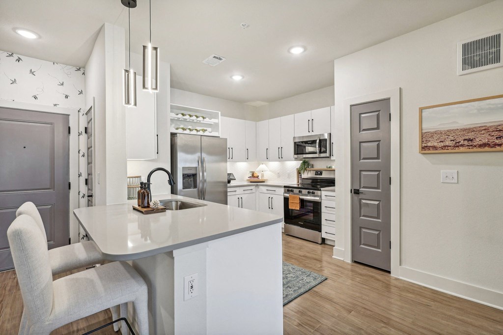 an open kitchen and dining area with white cabinets and stainless steel appliances