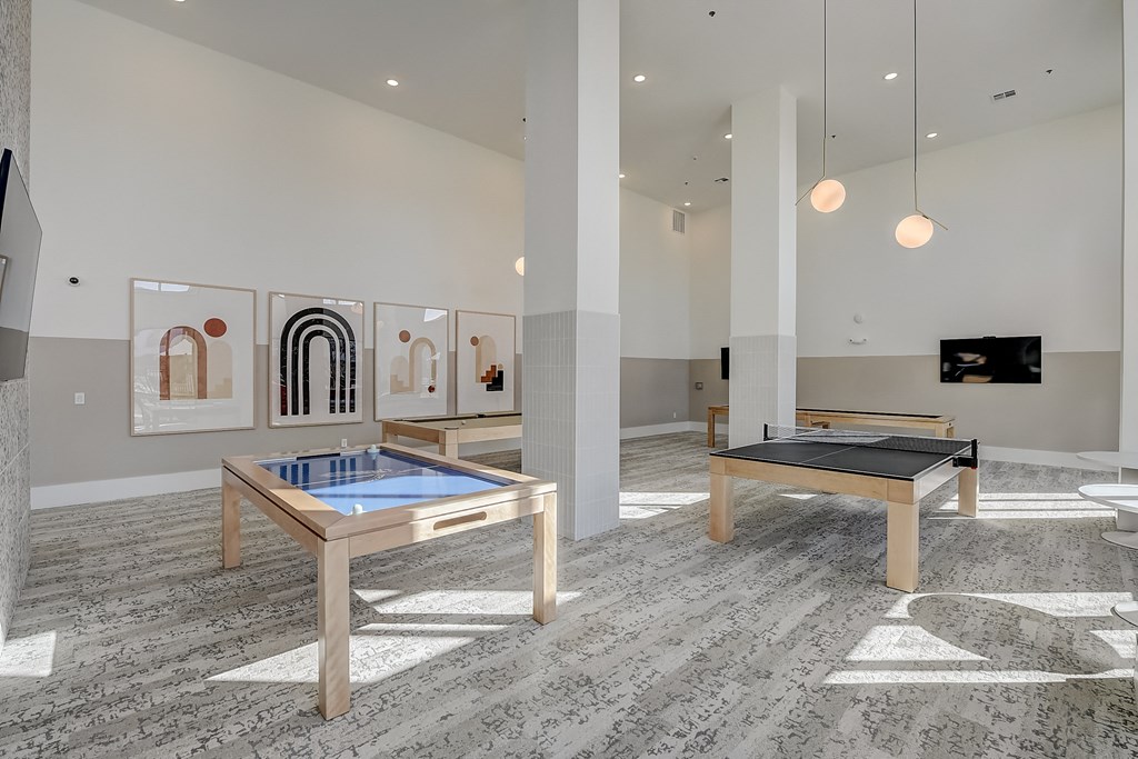 a room with two ping pong tables and paintings on the wall