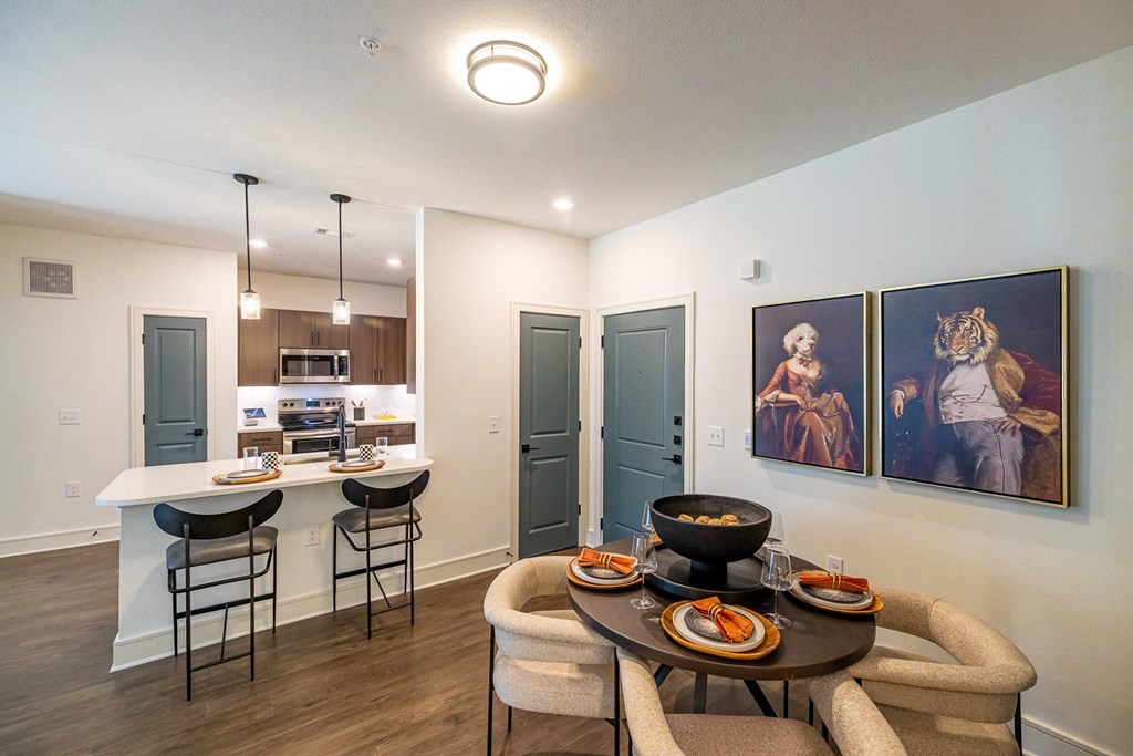 a living room with a table and chairs and a kitchen with a sink