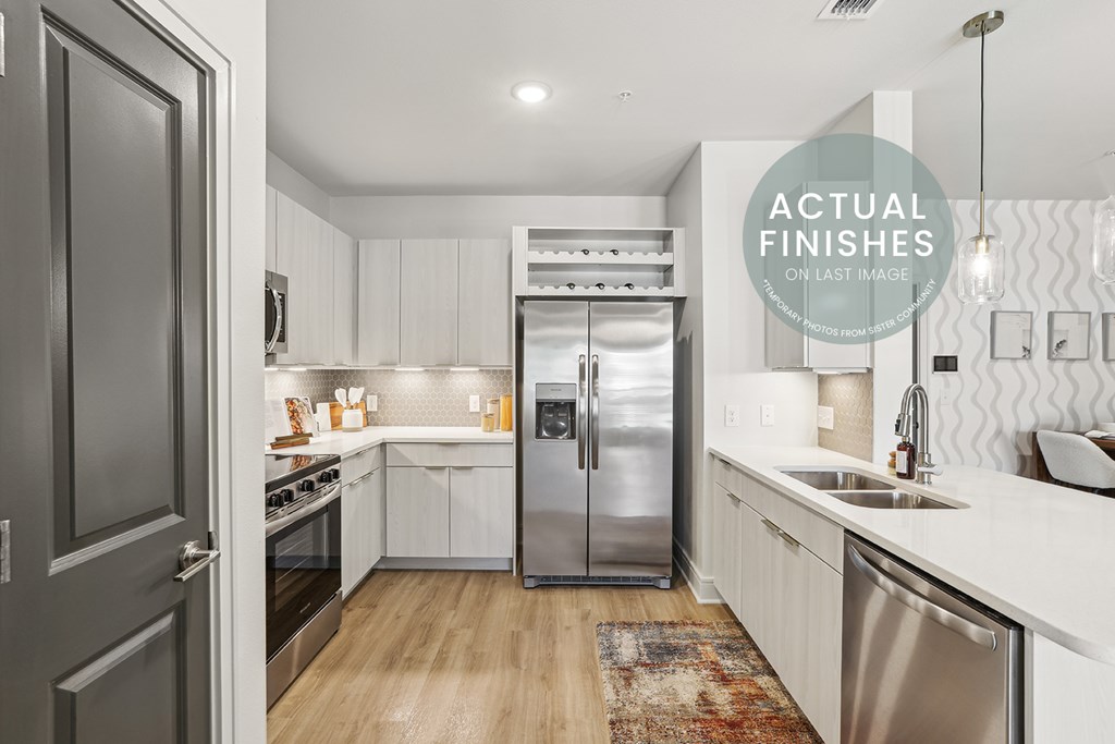 A modern kitchen with a stainless steel refrigerator and wooden flooring.