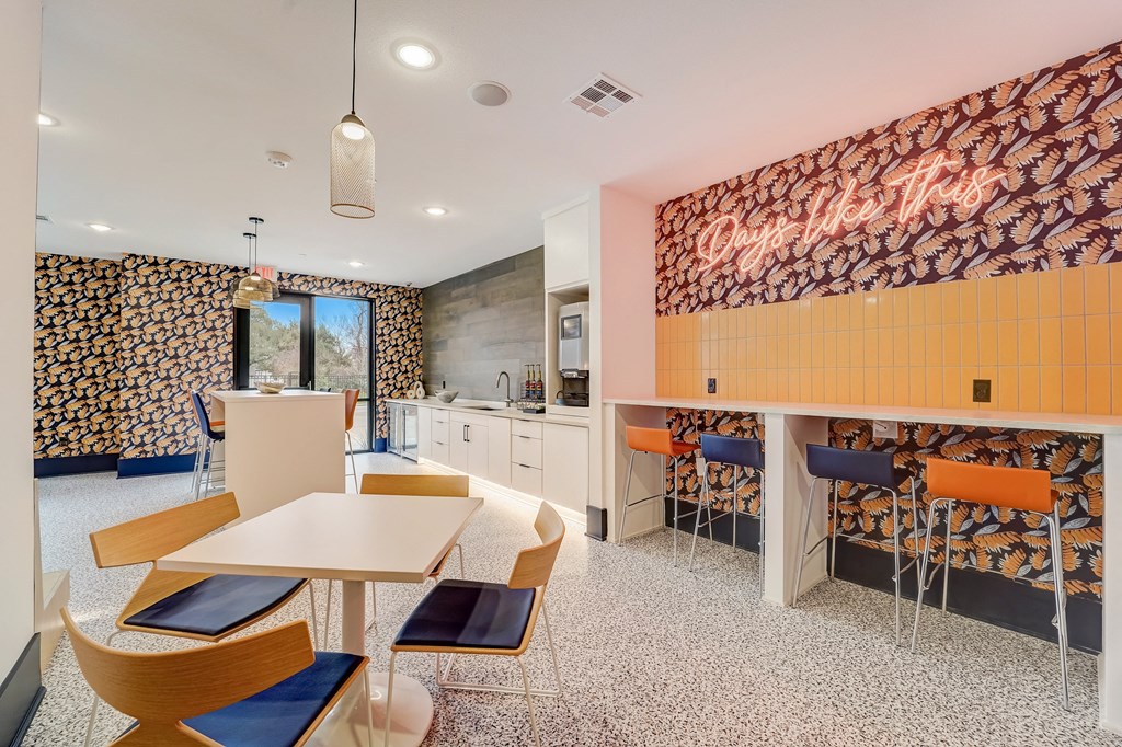 a dining area with tables and chairs and a counter with a bar and a kitchen
