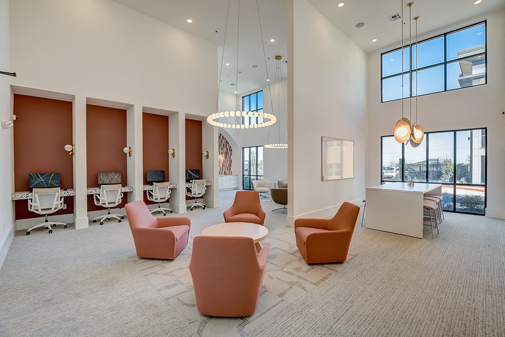 a lounge area with chairs and tables in a room with large windows