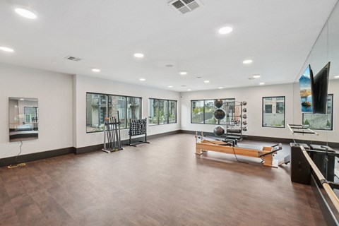 A spacious room with wooden floors and a variety of exercise equipment.
