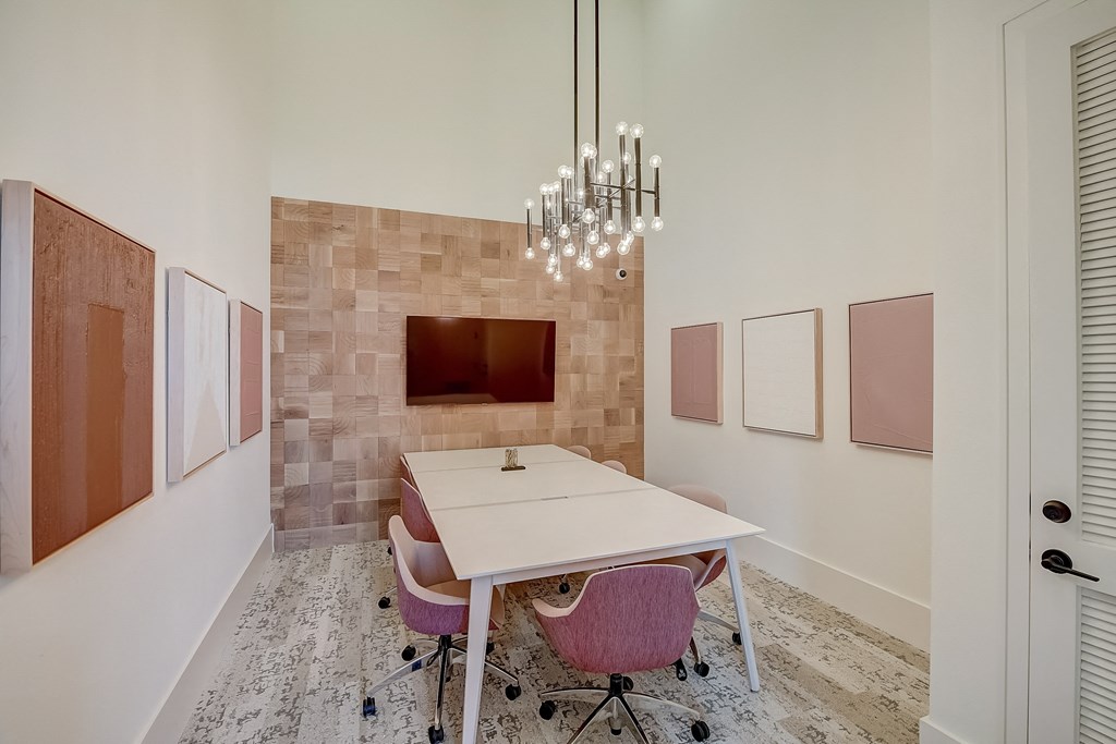 a conference room with pink chairs and a white table and a television