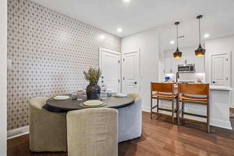 A dining room with a table set for two and a patterned wallpaper.
