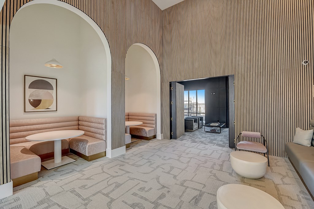 a lobby with two toilets and tables and a hallway with arched doors