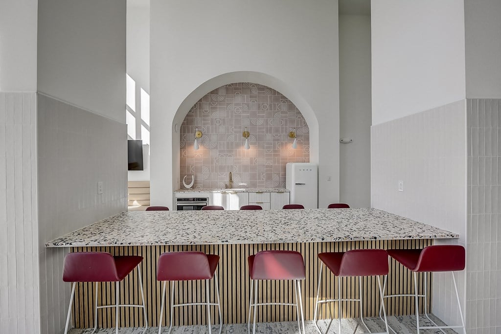 a kitchen with a marble counter top and red chairs