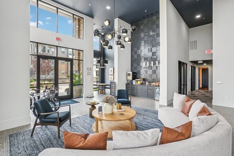 A modern living room with a grey sofa, a wooden coffee table, and a glass door leading to a balcony.