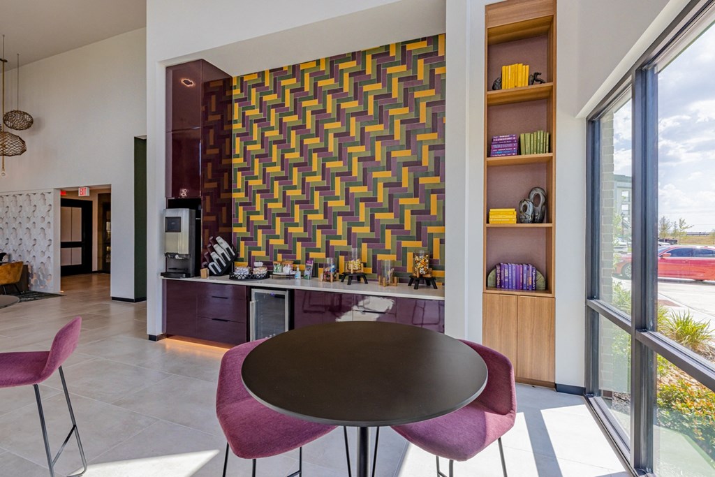a dining area with a round table and chairs and a wall with a geometric pattern