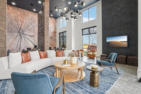 A modern living room with a white sofa, blue chairs, and a wooden coffee table.