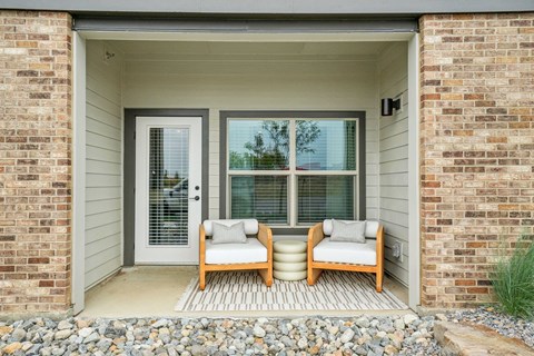 A small porch with two chairs and a table.