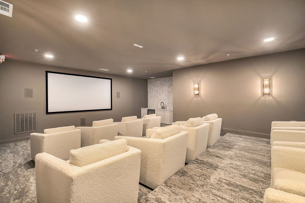 a theater room with white chairs and a projector screen
