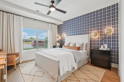 A bedroom with a bed, dresser, and window with curtains.
