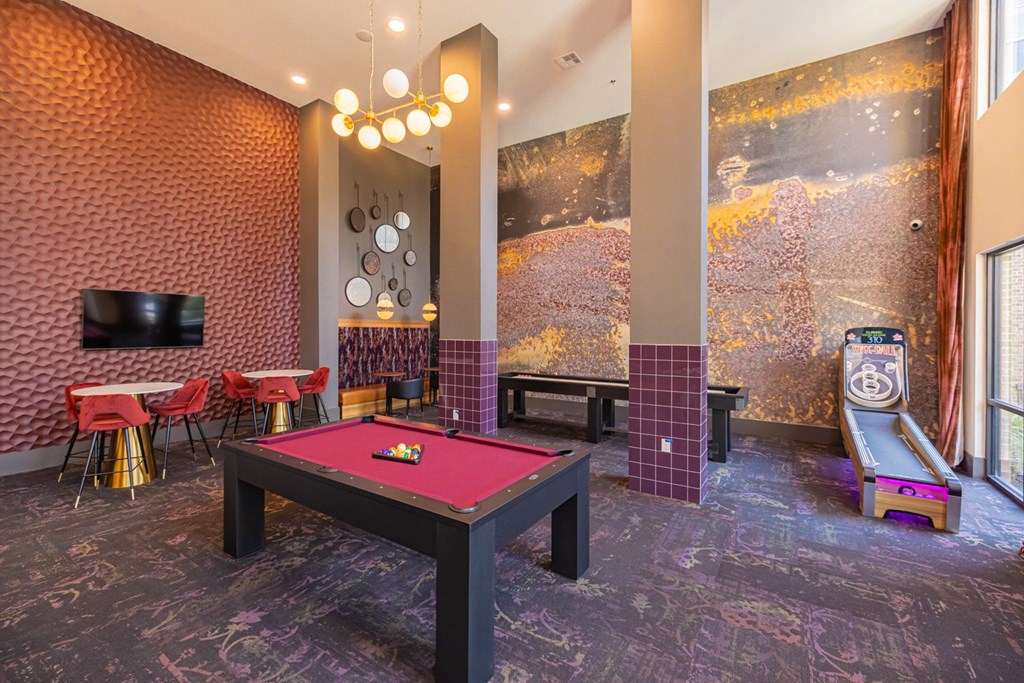 a game room with a pink pool table and a video game