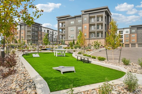 A park area with benches and a lawn in front of apartment buildings.
