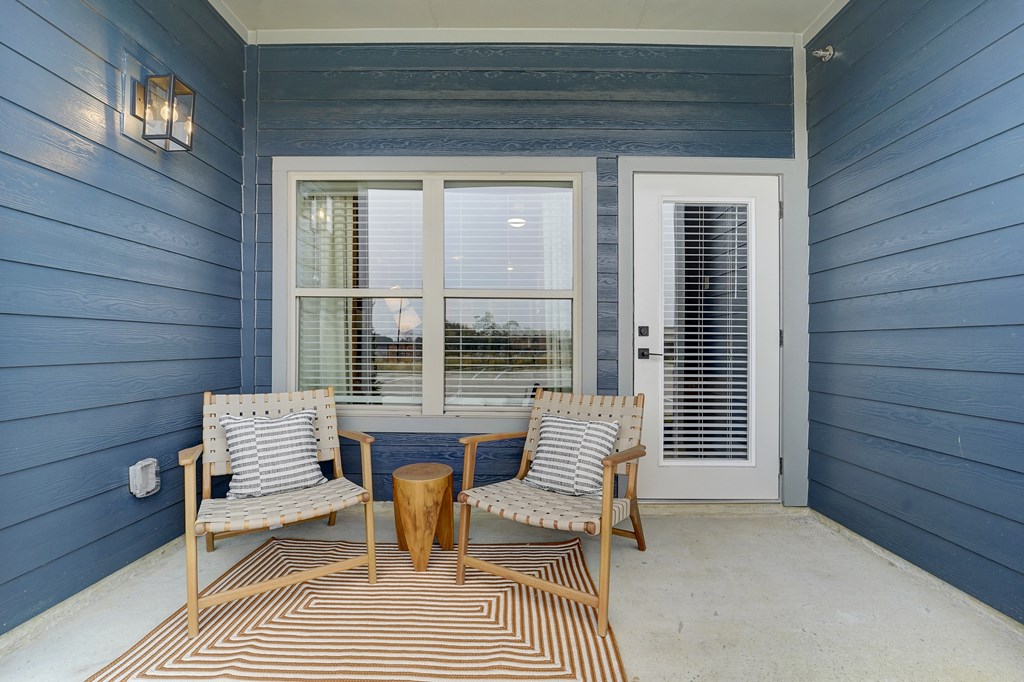 a porch with two chairs and a table and a blue wall