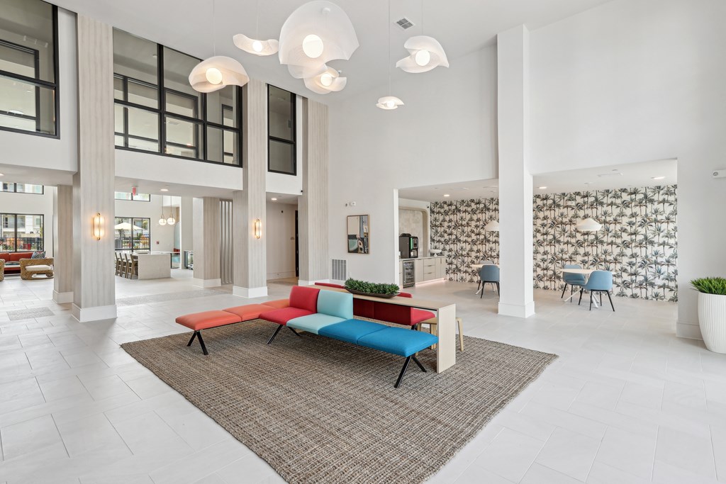 A modern lobby with a white floor and a large area rug.