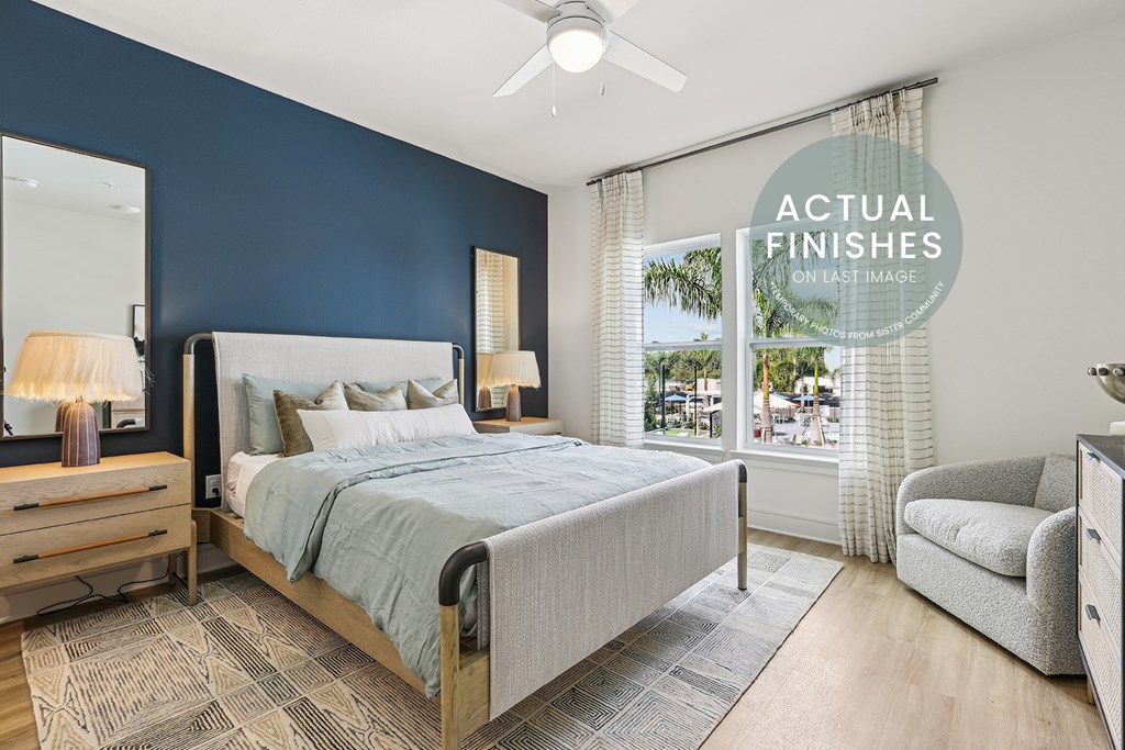 A bedroom with a bed, chair, and a mirror.