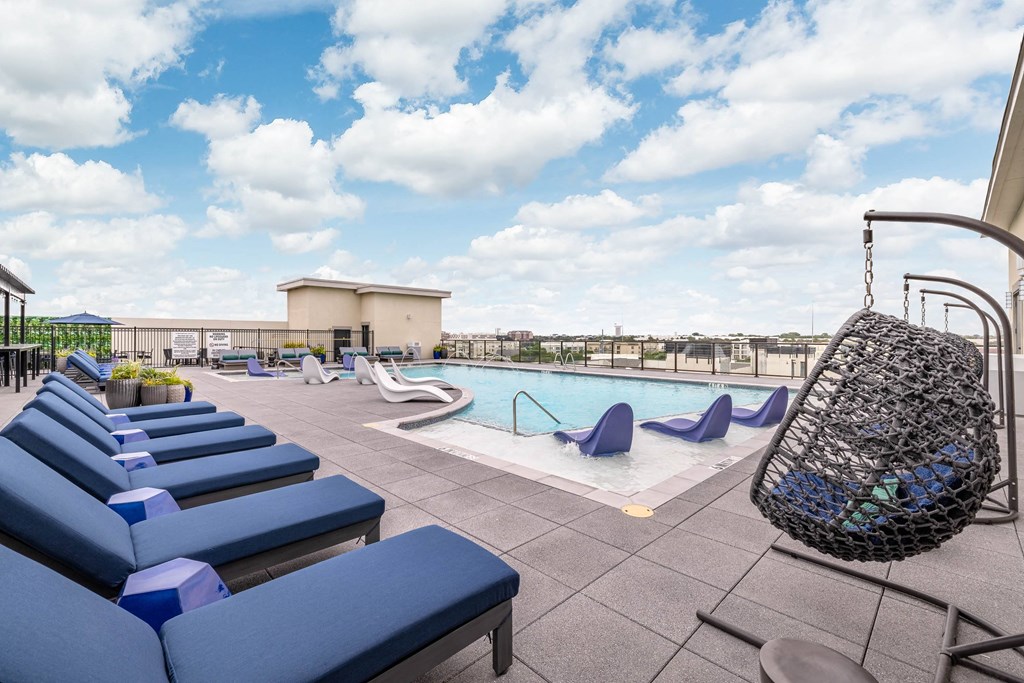 a swimming pool with blue lounge chairs and a swing on the side of a building