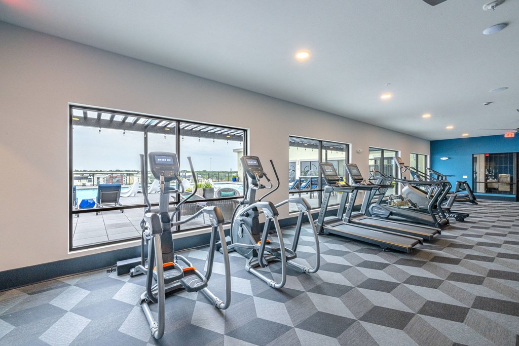 a gym with cardio equipment and a view of the water