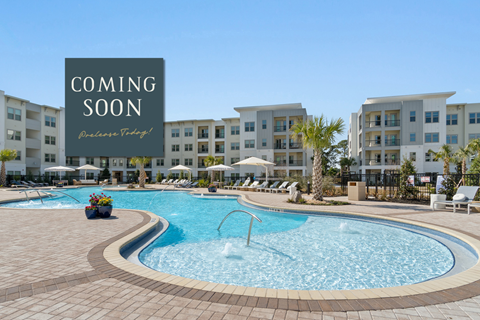 A pool area with a sign that says "Coming Soon" in front of apartment buildings.