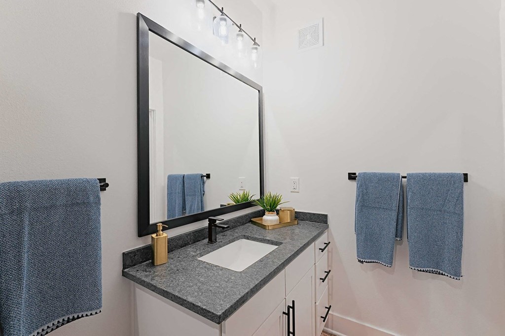 a bathroom with a sink and a mirror and blue towels