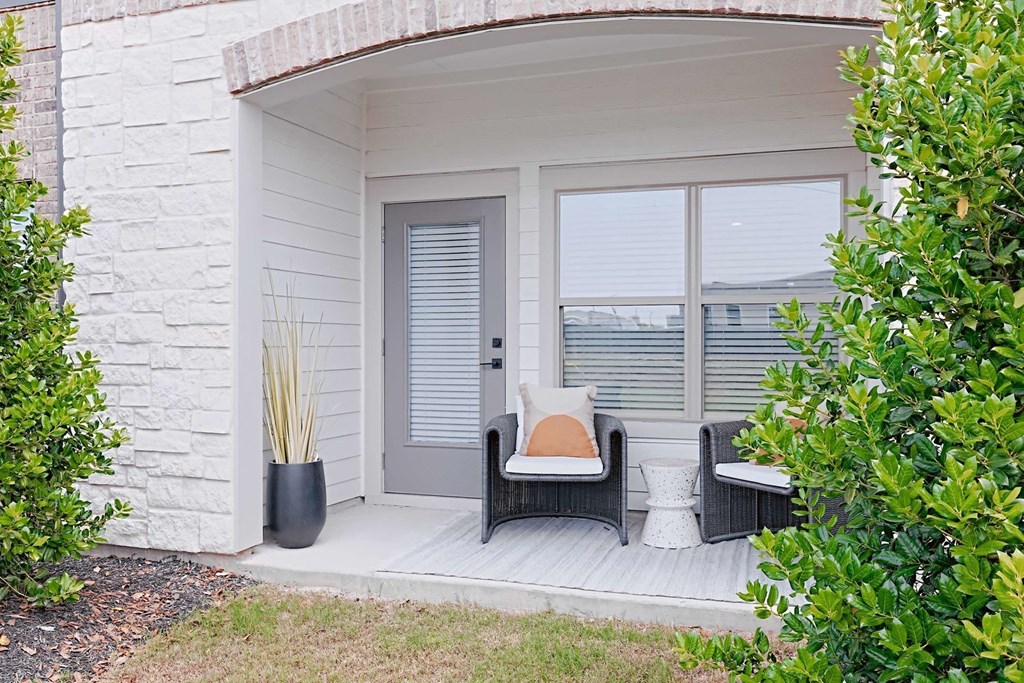 a small porch with two chairs and a pillow on it