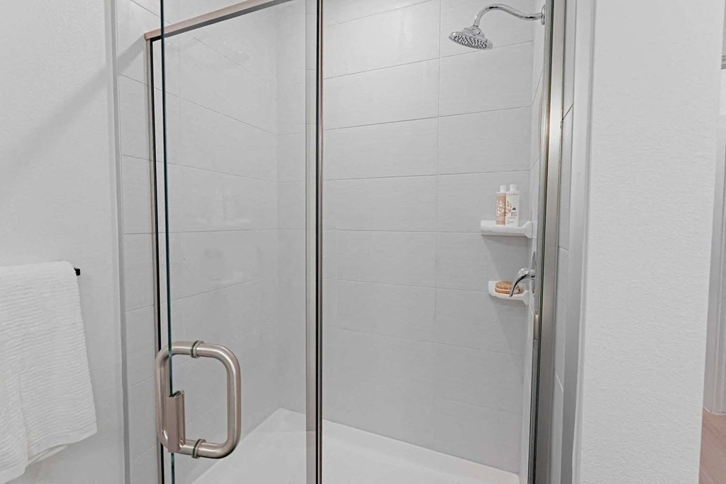 a shower with a glass door in a white bathroom
