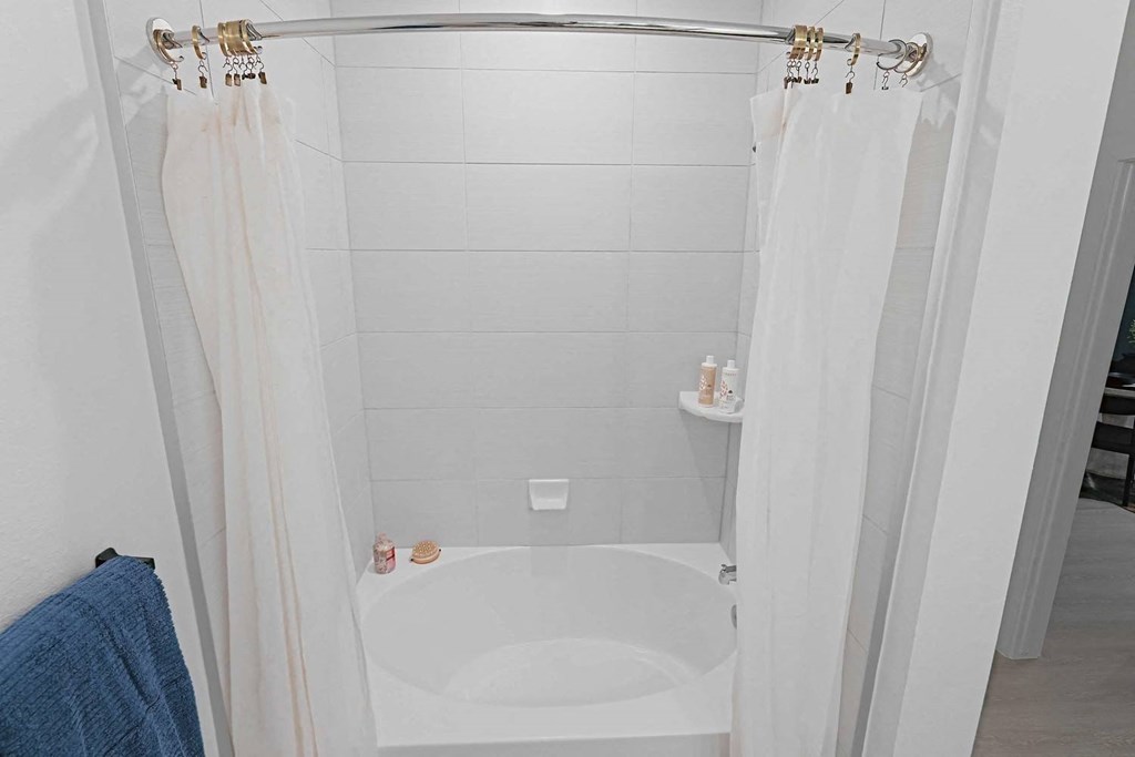 a white bathroom with a tub and a shower curtain