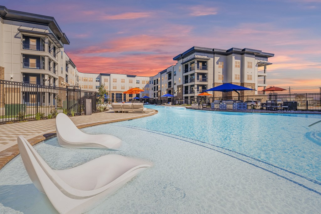 a swimming pool with chairs and umbrellas at dusk