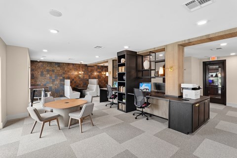 A modern office space with a brick wall and a variety of chairs and desks.
